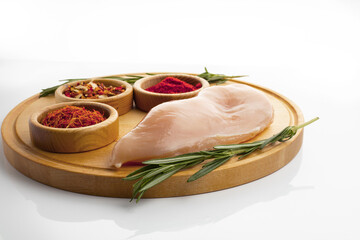 fresh chicken fillet with ingredients and spices and rosemary on a wooden board and white background