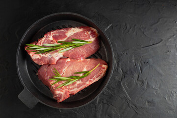 fresh delicious juicy meat steaks delicacy on a black pan with rosemary and spices on a black table with free space for text