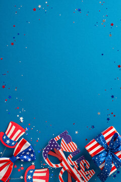 Fourth of July celebration setup with vertical top view of party accessories, confetti, headband, eyeglasses, bow-tie, giftbox, on a blue backdrop featuring an empty frame for text or advertisement