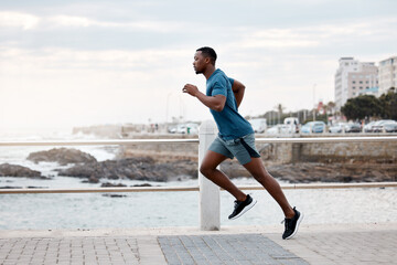 Black man, runner and exercise outdoor on beach promenade for fitness, training or cardio workout....