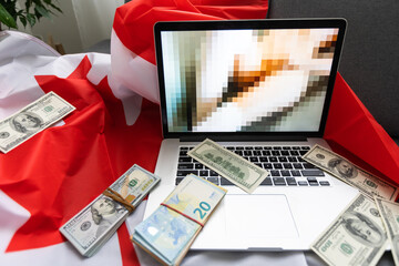 laptop with blurred screen, money and Canadian flag