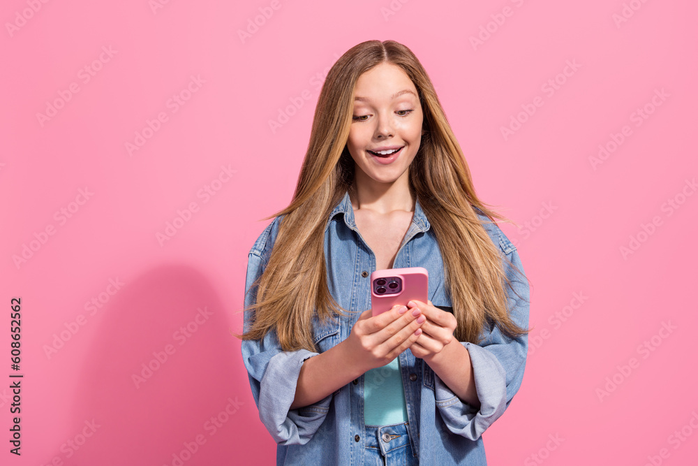 Sticker Portrait of gorgeous excited girl wear trendy clothes use modern telephone iphone reading facebook news isolated on pink color background