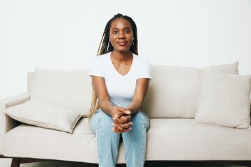 Fototapeta na wymiar Happy african american woman sitting at home on sofa, rest and vacation smile, light background. Relaxed home lifestyle, day off.