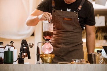 Professional coffee maker - Barista using coffee siphon brewing hot espresso at coffee shop coffee...