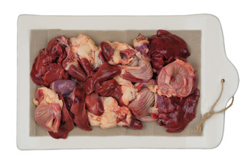 Raw chicken giblets on a ceramic board isolated on white background. Chicken stomachs, hearts and livers are prepared for cooking.