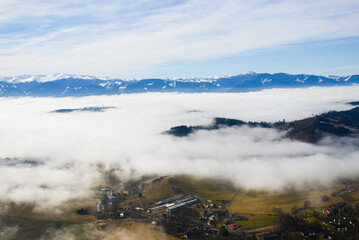 View from Cerenova skala (rock) in West Tatras  in Liptov. Near Liptovsky Mikulas city in foggy weather. Spring time, cloudy weather, Slovakia. Green forest. Village in the fog.
