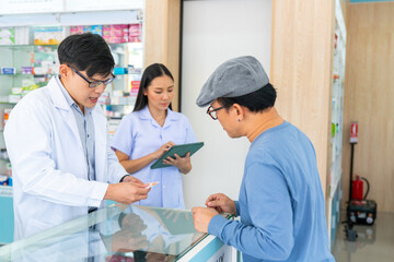 Obraz premium Medical pharmacy and healthcare providers concept. Professional Asian man and woman pharmacist recommend and selling medical product, medicine, drugs and supplements to patient customer in drugstore.
