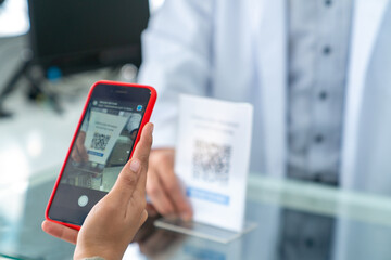 Medical pharmacy and contactless payment concept. Asian woman patient customer using mobile phone scan QR code on counter making online baking payment buying medicine and supplements in drugstore.