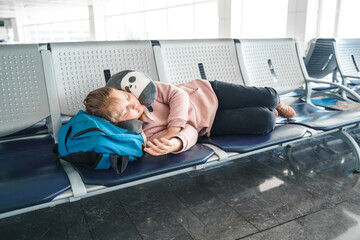 Kid, teen tired girl sleeping, waiting in airport passenger terminal departure hall with backpack....