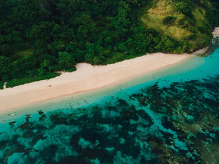 Tropical beach with cliffs and ocean in Bali island. Aerial view of vacation beach