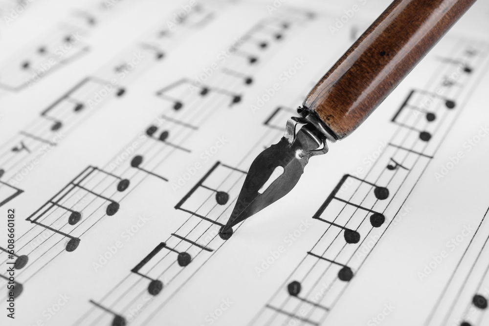 Wall mural writing musical notes with fountain pen on sheet of paper, closeup view