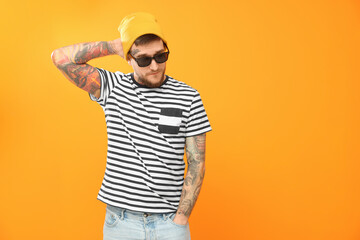 Handsome hipster man wearing stylish sunglasses on orange background. Space for text