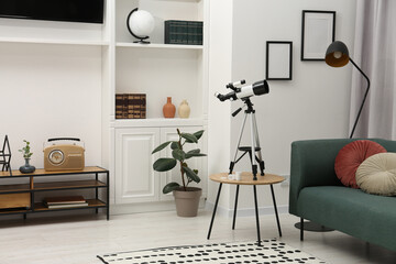 Tripod with modern telescope on table in living room © New Africa