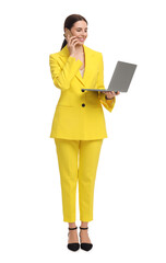 Beautiful businesswoman in yellow suit with laptop talking on smartphone against white background