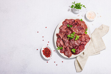 Raw chicken liver on stone background. Fresh ingredients ready for cooking, parsley, red pepper