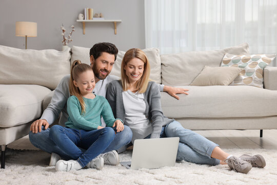 Happy family with laptop on floor at home