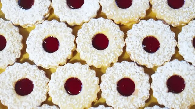 selbstgebackene Spitzbuben Pl&auml;tzchen f&uuml;r Weihnachten mit Puderzucker auf einem goldenen Teller