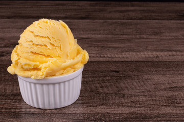 Delicious yellow ice cream served in a white pot. Tasty traditional yellow gelato enjoyed around the world. Food on the left with space for texts on the right.