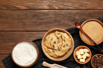 Fresh dough and different ingredients for cooking chocolate chip cookies on wooden table, flat lay. Space for text