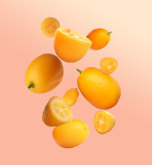 Delicious whole and cut kumquats falling on color background