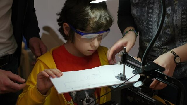 Young boy wearing safety goggles carefully learning wood carving techniques under supervision on a specialized workstation. Craftsmanship in Education: Fostering Fine Motor Skills.