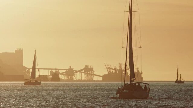 People sailing - sunset and industrial background