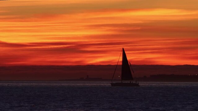 Landscape of bright red sunset and sailing boat