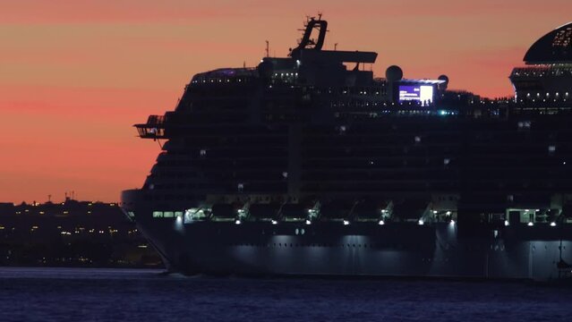 A huge cruise liner sails down the river at sunset