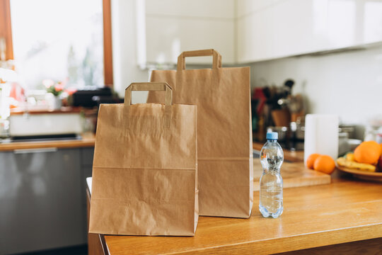 Two Food craft bags and water on the table on sunny day. Delivery in any weather around the clock to the client. Fast food eco packaging with big breakfast or diner set
