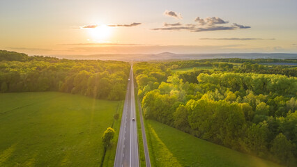 sunset over the road going through the forest, high angle view 