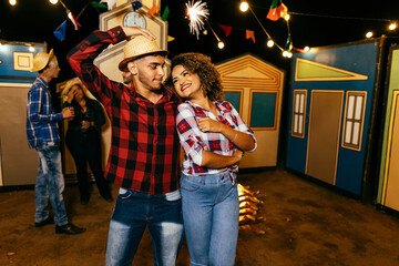 Couple dancing to Festa Junina, a lively Brazilian June festival with music, decorations, and...