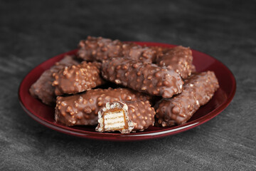 Plate of tasty chocolate bars with caramel on light grey table