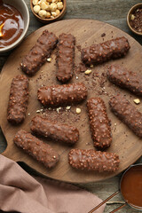 Tasty chocolate bars with caramel and nuts on wooden table, flat lay