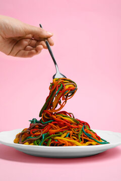 Woman Eating Delicious Spaghetti Painted With Different Food Colorings On Pink Background, Closeup