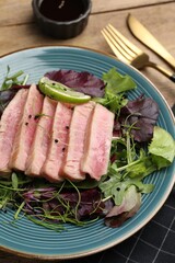 Pieces of delicious tuna steak with salad served on wooden table, closeup