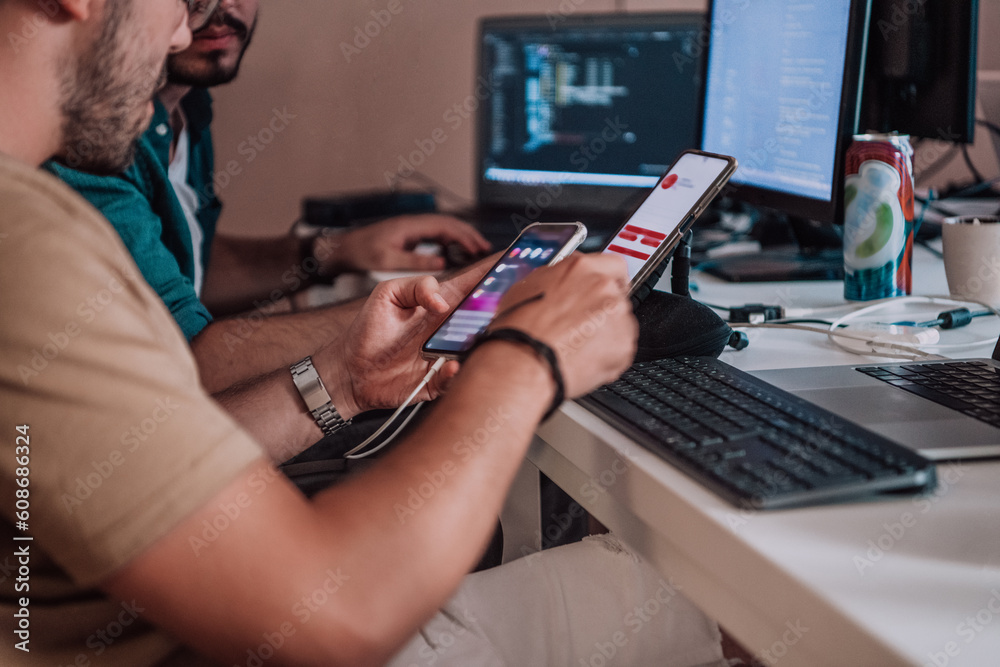 Wall mural a programmer diligently testing smartphone applications while sitting in their office.