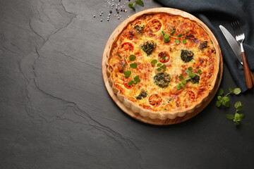 Delicious homemade vegetable quiche, oregano and cutlery on dark table, flat lay, Space for text