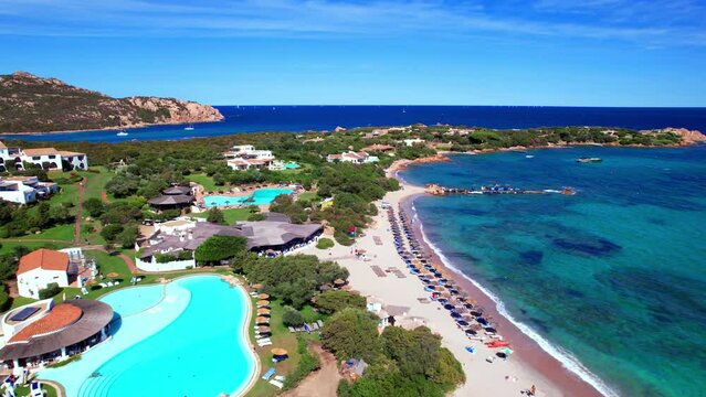 Luxury hotel Romazzino empty swimming pool 4K drone Sardinia. Costa Smeralda resort. Emerald coast Italy boutique hotel aerial view. Tropical turquoise sea beach travel footage Sardegna