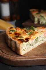 Piece of delicious homemade quiche with salmon and broccoli on wooden board, closeup
