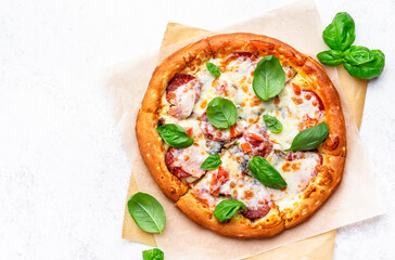 Pizza with spicy salami sausage, mozzarella cheese, tomato sauce and green basil, gray table background, top view