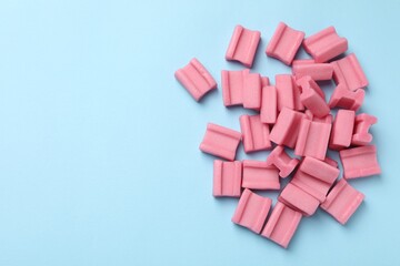 Tasty pink chewing gums on light blue background, flat lay. Space for text