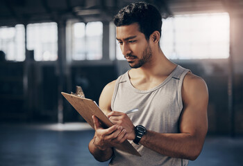 Sports, clipboard and male personal trainer in the gym working on a training schedule checklist. Young, confident and man athlete coach writing workout or exercise plan for wellness in fitness center