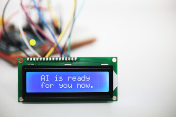 Blue LCD Display displaying the words 'AI is ready for you now' with a microcontroller and...