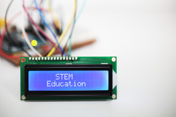Blue LCD Display displaying the words 'STEM Education' with a microcontroller and connecting wires...