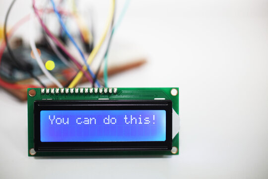 Blue LCD Display displaying the motivational message 'You can do this!' with a microcontroller and connecting wires blurred in the background. 