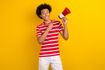 Photo of funky cheerful man dressed red t-shirt pointing finger bullhorn isolated yellow color background