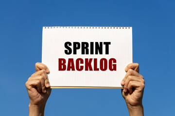 Sprint backlog text on notebook paper held by 2 hands with isolated blue sky background. This message can be used as business concept about sprint backlog.