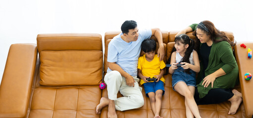 Fototapeta na wymiar Holiday and weekend. Happy young asian family sitting on sofa and playing video game in living room at home.