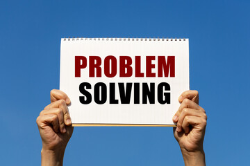 Problem solving text on notebook paper held by 2 hands with isolated blue sky background. This message can be used as business concept about problem solving.
