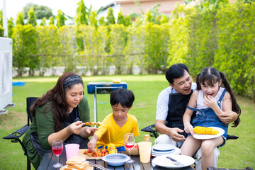 Home camping and cooking Barbeque party. Happy Asian family enjoying BBQ camping at home. Asian family in backyard garden at home.
